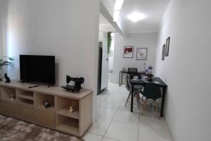 uma sala de estar com uma televisão e uma mesa com cadeiras em Apartamento Doce Aconchego - RESIDENCIAL WAKI 05 em Dourados