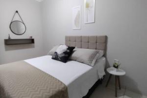 een witte slaapkamer met een bed en een bijzettafel bij Apartamento Doce Aconchego - RESIDENCIAL WAKI 05 in Dourados