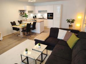 uma sala de estar com um sofá castanho e uma cozinha em Modern Mountain Apartment - free parking & sauna em Obertauern
