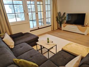 a living room with a couch and a tv at Modern Mountain Apartment - free parking & sauna in Obertauern