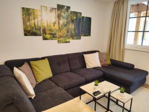 sala de estar con sofá marrón y pinturas en la pared en Modern Mountain Apartment - free parking & sauna en Obertauern