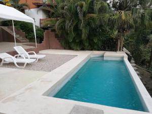 a swimming pool with two chairs and an umbrella at Deep Blu Apartment in Carmen