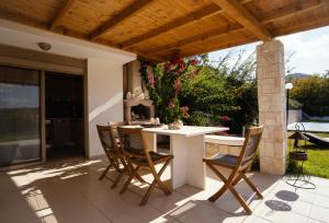 eine Terrasse mit einem Tisch und Stühlen unter einem Holzdach in der Unterkunft Villa Destiny in Pefkohori