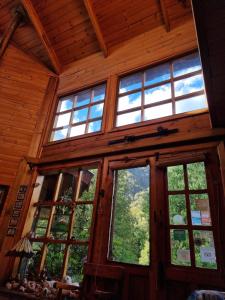 um quarto com janelas grandes num chalé de madeira em CasaVerde Hostal Ecologico em Malalcahuello