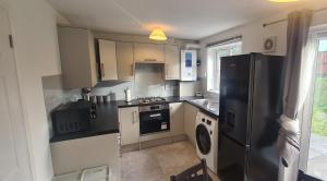 cocina con nevera negra y lavavajillas en Delightfully Decorated Home, Private Parking and Garden,Close to Abbey Wood and Woolwich Stations for Elizabeth Line Easy Access to Central London, West End,02,Greenwich Maritime Museum, en Thamesmead