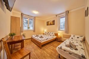 a room with two beds and a desk and two windows at Residence Ruth in Janske Lazne