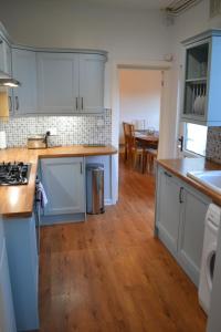 a kitchen with white cabinets and a wooden floor at Entire 3 bedroom house near Caerphilly station in Caerphilly