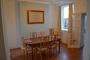 - une salle à manger avec une table, des chaises et un miroir dans l'établissement Entire 3 bedroom house near Caerphilly station, à Caerphilly