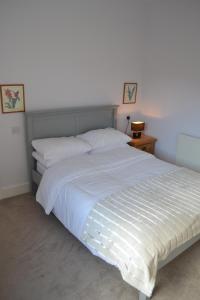 a bedroom with a large white bed with white sheets at Entire 3 bedroom house near Caerphilly station in Caerphilly