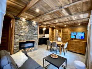 a living room with a table and a stone fireplace at Chalet Les Cocales Résidence Séjour et nuitées B&B - Appartement Pin Cembro in Bessans