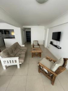 sala de estar con sofá, sillas y TV en Semipiso Ecos del Mar en Necochea