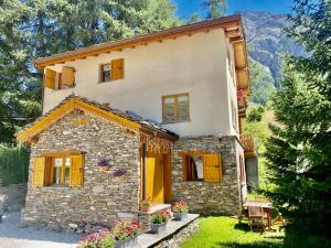 a stone house with yellow shutters on the side of it at Chalet Les Cocales Résidence Séjour et nuitées B&B - Appartement Pin Cembro in Bessans