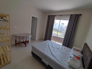 1 dormitorio con cama y ventana grande en Espaçoso apto bem localizado, en Bombinhas
