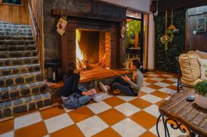 twee personen zitten op de vloer voor een open haard bij Hotel Rancho Constanza & Cabañas de la Montaña in Constanza