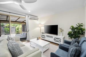 a living room with a couch and a tv at Regency 3 Bedroom Central Town House in Mooloolaba