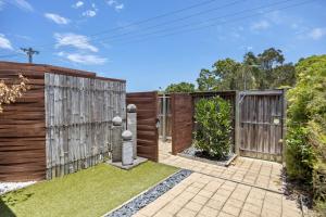 a garden with a fence and a wooden gate at Regency 3 Bedroom Central Town House in Mooloolaba