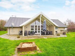 a house with a patio and an umbrella in the yard at Three-Bedroom Holiday home in Hemmet 35 in Hemmet