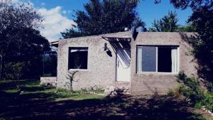una pequeña casa de piedra en un patio con árboles en Sacha Manta en Mina Clavero