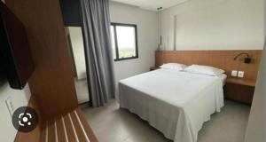 a bedroom with a white bed and a television at Salinas exclusive resort in Salinópolis