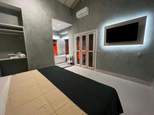 um quarto com uma cama e uma televisão de ecrã plano em Pousada do Rosa Camburi em Camburi
