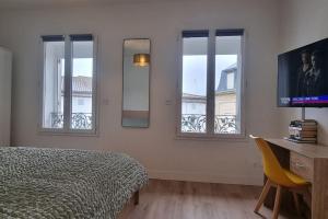 sypialnia z łóżkiem, biurkiem i oknami w obiekcie Appartement climatisé entièrement rénové en hyper centre! Le Rétro Chic - Parking gratuit - Linge et serviettes inclus - w mieście La Roche-Chalais