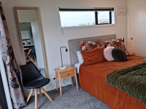 a bedroom with a bed and a chair and a mirror at Mangorei Heights - New Plymouth in New Plymouth