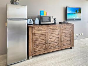 a stainless steel refrigerator next to a wooden cabinet with a tv at Blue on Blue Studio Room 1272 in Nelly Bay