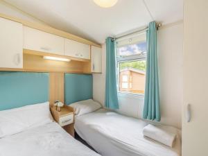 2 camas en una habitación pequeña con ventana en Apple Tree Lodge, en Swarland