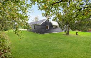 een zwart huis in een veld met een grasveld bij Cozy Home In Lgstr With Kitchen in Løgstør