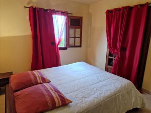 een slaapkamer met rode gordijnen, een bed en een raam bij beautifull wooden house in Saint-Claude