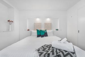 1 dormitorio blanco con 1 cama blanca grande con almohadas en Cosy Cottesloe - 2 Bedroom Unit - Free Parking - Free WIFI en Lindisfarne