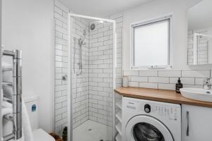 baño blanco con lavadora y lavamanos en Cosy Cottesloe - 2 Bedroom Unit - Free Parking - Free WIFI en Lindisfarne