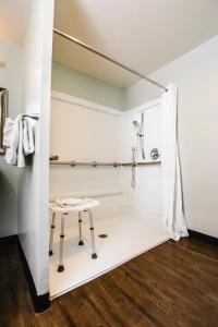 a walk in shower with a stool in a room at The Atwood Hotel San Diego - SeaWorld/Zoo in San Diego