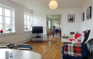 a living room with a tv and a table and chairs at 4 Bedroom Stunning Home In Gudhjem in Gudhjem