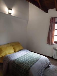 1 dormitorio con 1 cama con manta y ventana en Casa luminosa y Acogedora en Ushuaia