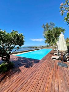 a wooden deck with a swimming pool next to the ocean at Luxury beach house with spectacular sea view and pool in Trou aux Biches