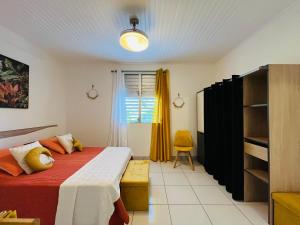 ein Schlafzimmer mit einem Bett und einem gelben Vorhang in der Unterkunft Appartement Manou in Le Lamentin