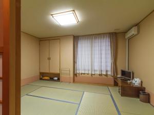 an empty living room with a television and a window at Assabu Uzura Onsen Shiki no Yado 