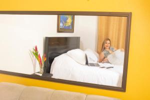 a woman sitting on a bed with a laptop in a mirror at Black Snapper House in Golfito