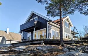 een zwart huis met een boom ervoor bij Awesome Home In Risr With House Sea View in Risør