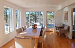 een eetkamer met een tafel, stoelen en ramen bij Awesome Home In Risr With House Sea View in Risør