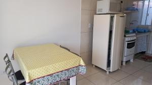 eine kleine Küche mit einem Tisch und einem Kühlschrank in der Unterkunft Sol Nascente Apartamentos - Pontal do Sul in Pontal do Paraná