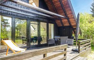 a house with a deck with chairs and a table at Awesome Home In Aakirkeby With Wifi in Vester Sømarken