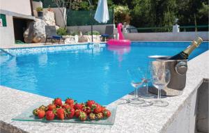 - une assiette de fraises et de verres à vin à côté de la piscine dans l'établissement 2 Bedroom Gorgeous Apartment In Ploce, à Ploče
