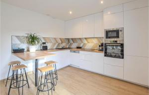 a kitchen with white cabinets and a table and stools at Beautiful Home In Angerville-lorcher With Wifi in Angerville-lʼOrcher