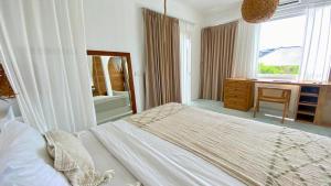 a bedroom with a bed and a desk and a window at Guru Canggu in Canggu