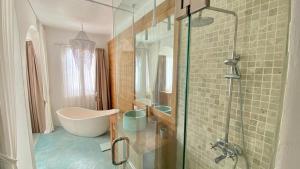 a bathroom with a tub and a glass shower at Guru Canggu in Canggu