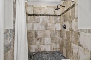 a bathroom with a shower with a stone wall at Cozy Lake Home - Jacuzzi King Bed Marina Access in Mooresville +18 photos