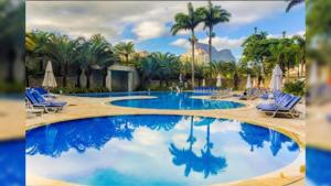 una gran piscina con sillas y palmeras en Apart hotel Twin Towers, en Río de Janeiro