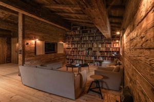 eine Bibliothek mit Sofa, Stühlen und Bücherregalen in der Unterkunft Luxury old wood mountain chalet in a sunny secluded location with gym, sauna & whirlpool in Scheffau am Wilden Kaiser